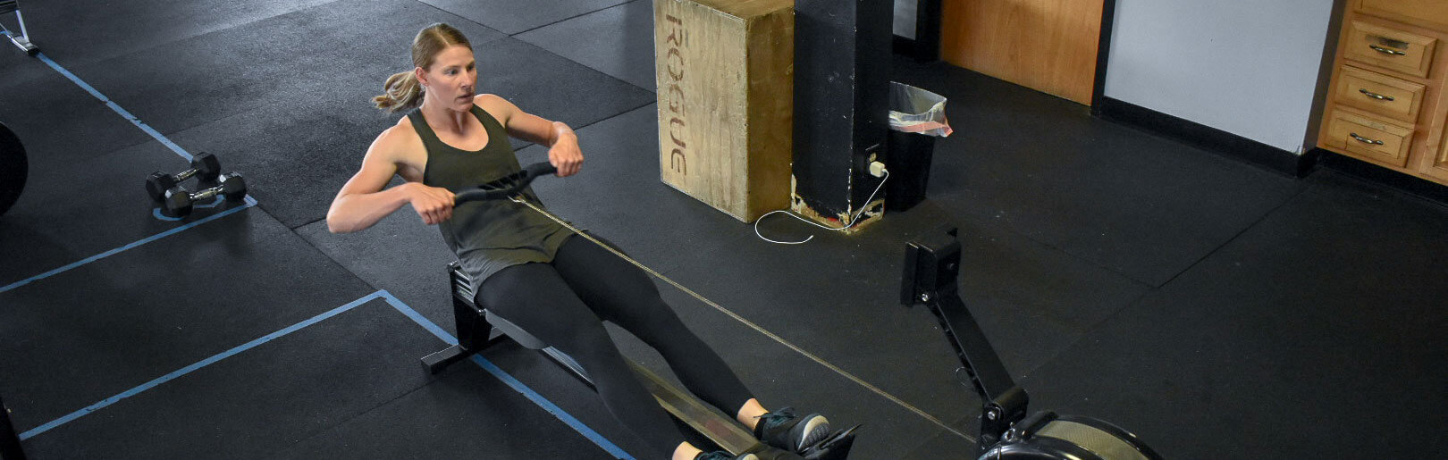 Female member rows on Concept 2 machine at CrossFit Alaska.
